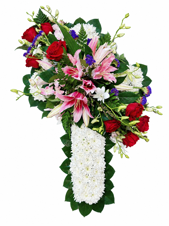 A large floral arrangement in the shape of a cross, featuring pink lilies, red roses, white carnations, and green foliage on a plain white background.