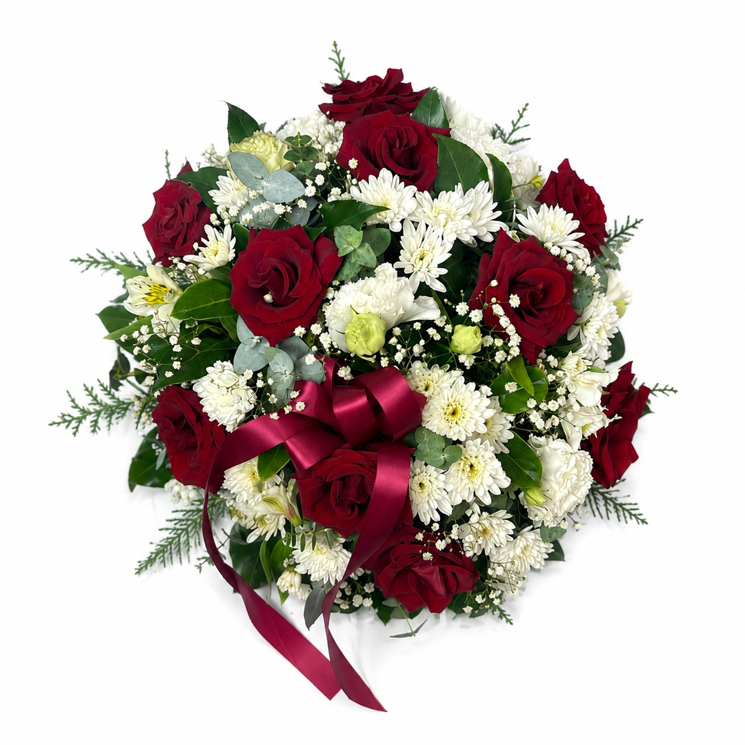 Ruby Remembrance red and white posy pad tribute featuring premium red roses, white chrysanthemums and fresh seasonal foliage arranged in a classic circular funeral tribute.