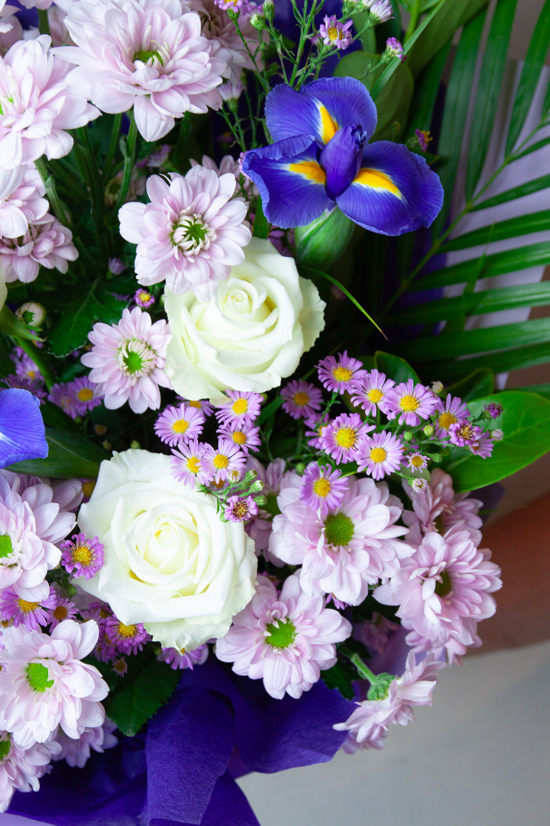 Bouquet of flowers including white roses, purple and yellow iris, and other assorted flowers.