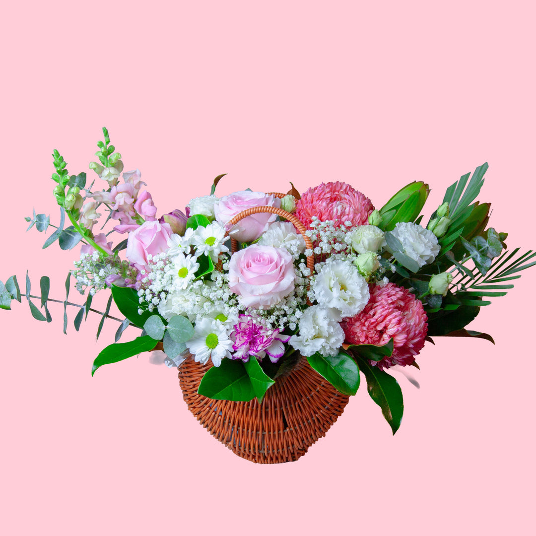 Cottage Garden Basket featuring pink roses, seasonal flowers, lisianthus and fresh foliage arranged in a woven basket.