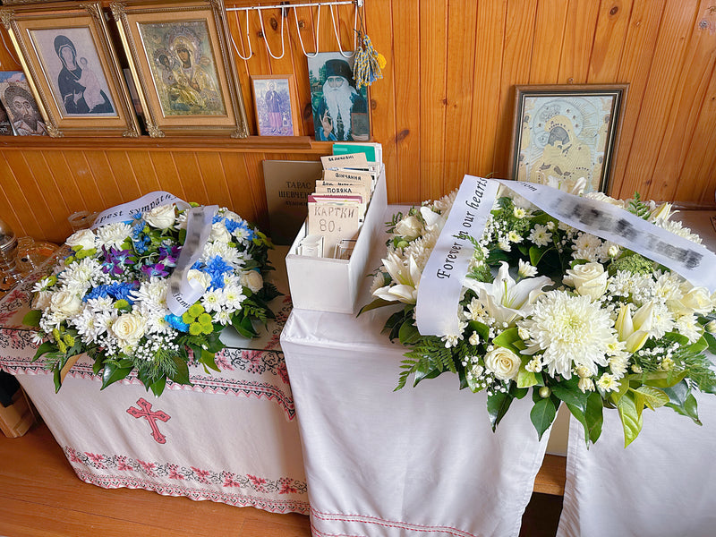 white lilies and white roses funeral wreath with blue and white funera wreath