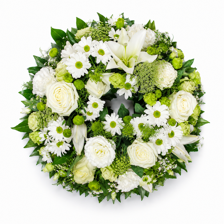 Evergreen Grace funeral wreath featuring white roses, lilies, chrysanthemums and fresh green foliage arranged in a classic circular tribute.