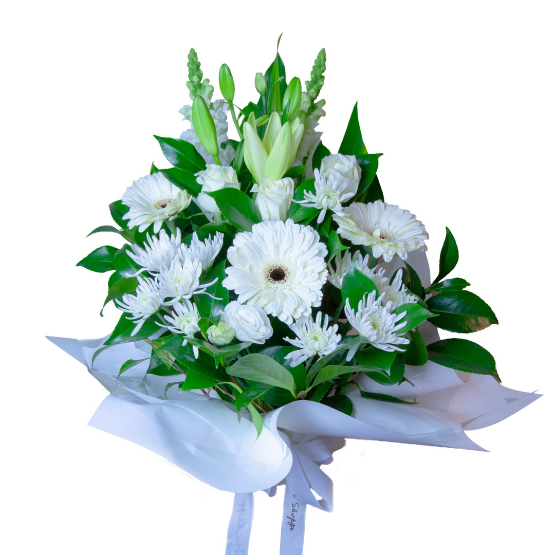White Haven white flower arrangement featuring oriental lilies, premium white roses, gerberas, chrysanthemums, lisianthus and fresh seasonal foliage in a ceramic container.