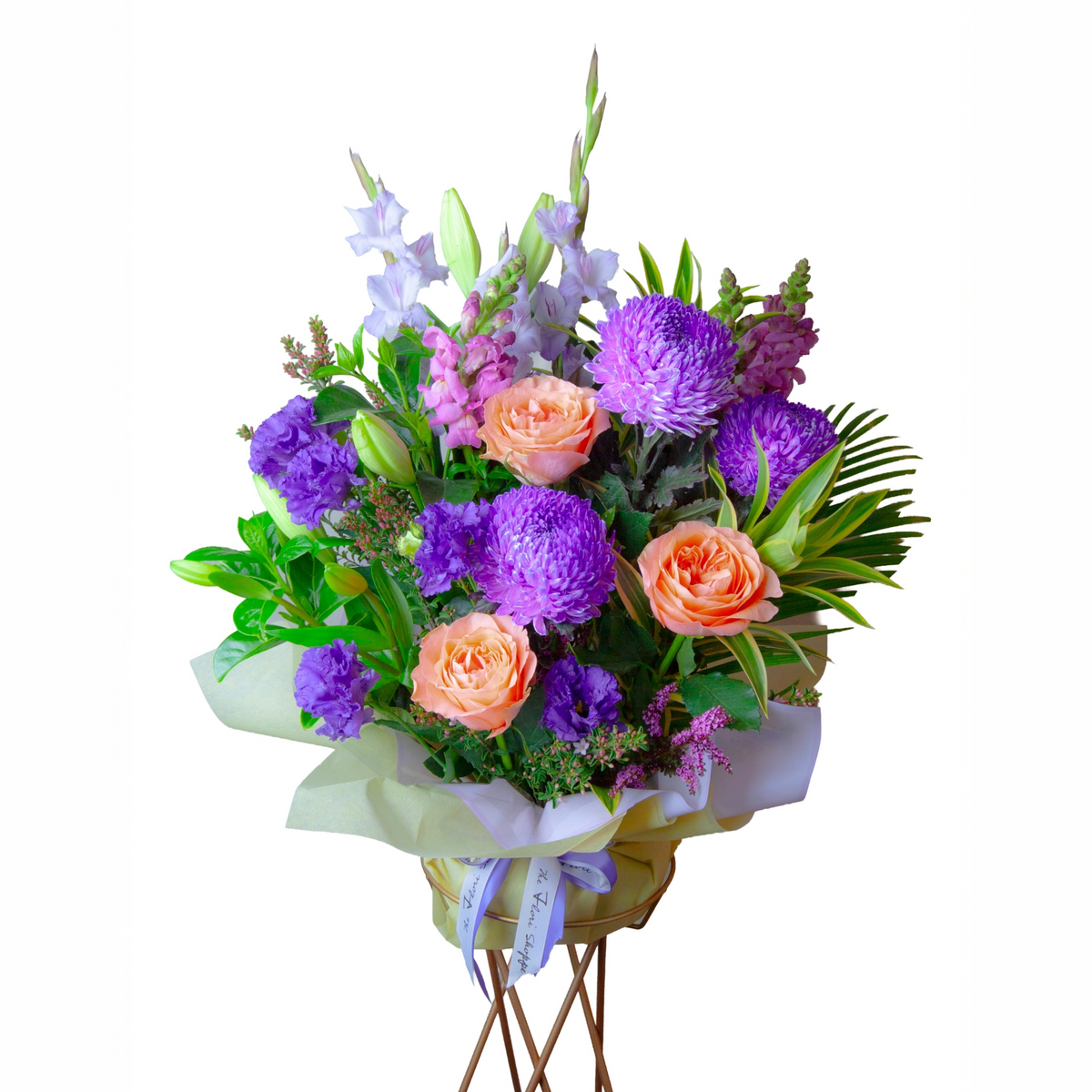 Eden Garden flower arrangement featuring peach roses, purple chrysanthemums, lilies, snapdragons, lisianthus and seasonal foliage in a premium garden style.