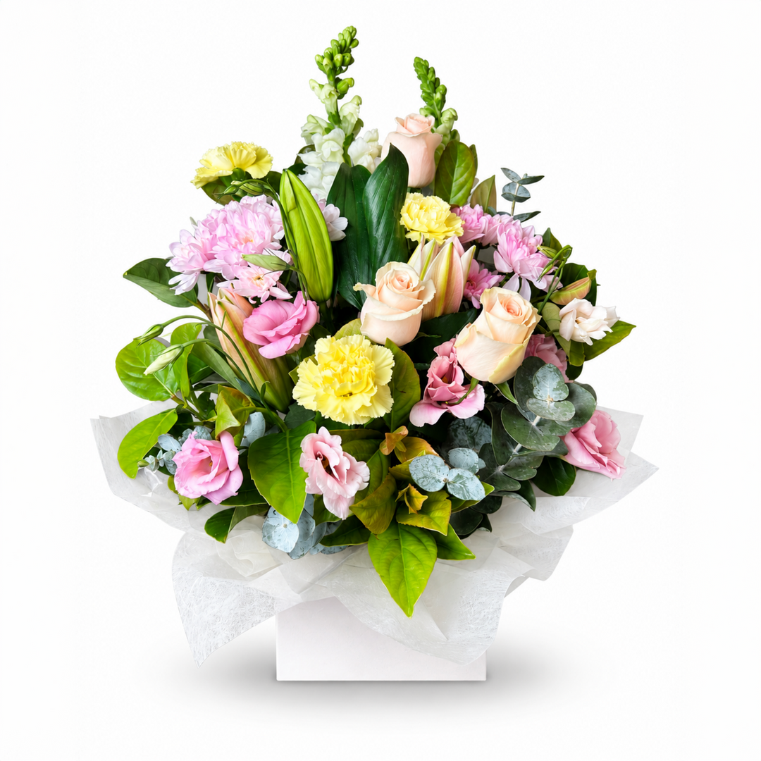 Pastel Garden flower arrangement in a white box with soft pink and peach roses, yellow carnations and white snapdragons