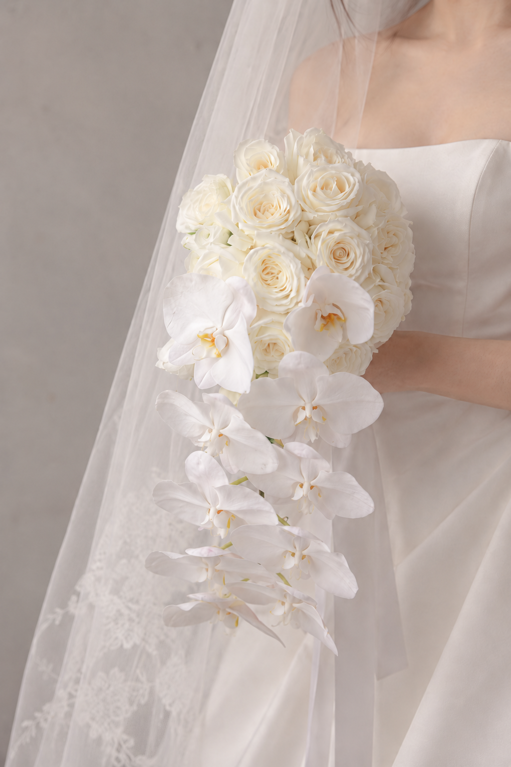 White orchid and Ecuadorian rose bridal bouquet held by bride in modern wedding dress